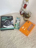 Group shot of the three sealed camera cleaning kits on carpet
