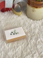 Gem case with seven square green tourmaline stones on white pad
