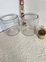 Two cylindrical clear glass jars, no lids, shown side by side