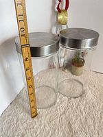 Both glass canisters side by side with tape measure showing 9 in height