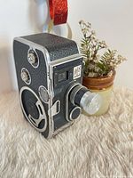 Front and left side view of Bolex B8 camera showing lens, leatherette body, and controls