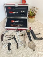 Group view of all openers with aluminum case open showing four-piece wine set