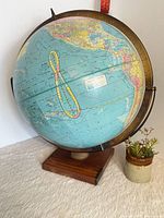 Full view of globe on stand showing Pacific region, brass meridian, wood base