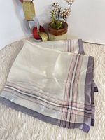 Full view of folded silk handkerchief showing purple border and stripes