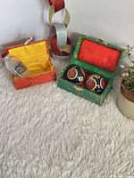 Baoding balls in green brocade box and snuff bottle in red brocade box on rug