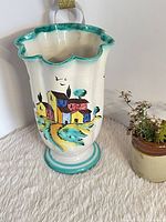 Full view showing flared rim, village scene and pedestal base