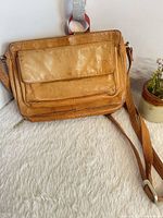 front view of tan leather crossbody bag showing front flap pocket and strap