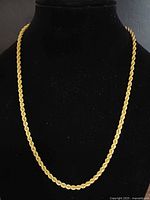 Front view of full necklace on bust, showing rope design and gold tone