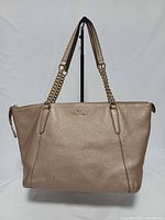 Front view of Coach Ava tan pebbled leather tote, showing gold-tone chain straps and logo