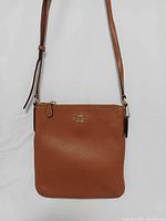 Front view showing Coach logo, brown crossgrain leather, vertical shape and strap