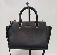 Front view of black Michael Kors Selma satchel showing logo, handles and shape