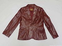 Front view of burgundy leather jacket showing lapel, pockets, buttons, lining label