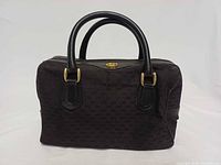 Front view of black micro GG Gucci Boston handbag showing rolled handles and gold hardware