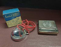 Smoker's Robot with box, red cord, and Motor Hollyhawk cigarette case