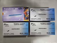 Four sealed boxes of blue nitrile gloves displayed on surface