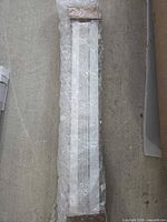 Bundled white faux wood blind wrapped in bubble wrap, wood-toned end caps visible