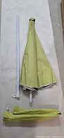 Umbrella canopy folded, white pole sections, green sleeve