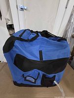 Front view of blue AmazonBasics soft pet crate showing pocket and mesh panels