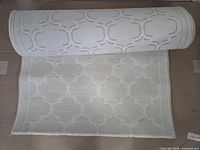 Rolled and partially unrolled off-white carpet runner showing geometric trellis pattern