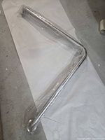Full view of L-shaped grab bar in plastic wrap