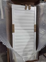 White vinyl louvered window shutter panel in packaging