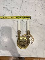 Front view showing two-arm brass sconce with rope motif, tape for scale