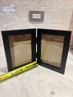 Frame open showing interior openings and tape measure indicating approx 3.5" x 5" viewable area