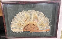 Front view of framed lace and wood fan in shadowbox