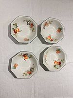 Top view of four octagonal bowls showing interior fruit and floral design and green rims