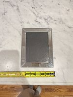 Front view of mirrored glass photo frame with tape measure showing width
