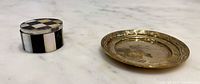 Closed pill box and brass dish on marble surface