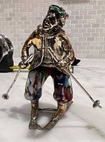 Front view of silver-plated skier figurine showing multicolour Murano glass pants and ski poles