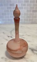 Full view of frosted pink and peach marbled glass perfume bottle with stopper