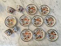 Nine plates and four cups displayed top-side