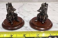 two assembled figurines on bases with measuring tape for scale