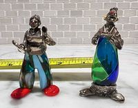 Front view of both clown figurines with measuring tape for scale