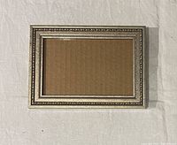 Front view of silver-leaf wood frame showing opening and ornate border