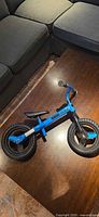 Full view of blue Neon balance bike on floor