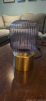 Full view of lamp showing smoked ribbed glass shade and brass base