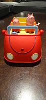 Front view of red car with two Peppa Pig figures seated