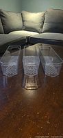 three clear plastic bins standing upright showing hand-grip ends and checker pattern