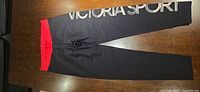 Full view front of black leggings with red waistband and large Victoria Sport logo