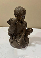 Front view of seated boy with dog figurine
