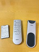 All three Bose Wave remotes side by side on table
