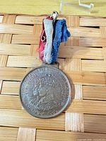 Front of medal showing portraits, text, and ribbon