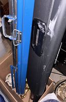 Blue Dalite screen housing next to black carry tube, showing latch and handle