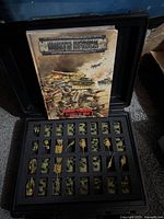 Open carrying case with foam holding painted miniatures and handbook displayed
