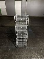 Front angled view of entire white wire basket rack showing eight baskets