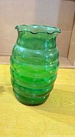 Front view of green ribbed glass vase with ruffled rim
