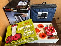 All three items: boxed kettle, blue cooler, boxed feeder with contents displayed